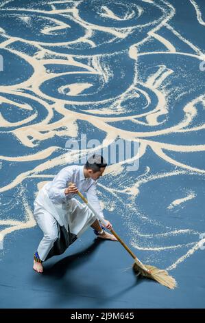 London, Großbritannien. 24 Mai 2022. Die Tate Modern inszeniert die erste britische Performance von Lee Mingwei's Our Labyrinth. Wird von morgens bis abends in der Turbinenhalle über einen Zeitraum von drei Wochen kontinuierlich durchgeführt. Unser Labyrinth verwandelt den einfachen Akt des Fegefens in eine kontemplative, gestische Performance, die ein Gefühl des Rituals in die Galerie bringt. Zwei Tänzer mit Glocken an ihren Knöcheln Formen die Körner zu einer Reihe labyrinthischer Pfade. Die Arbeit ist inspiriert von der Erfahrung des Künstlers, alte Tempel auf dem Land in Myanmar zu besuchen, wo Wege von Hütten zu Tempeln von Volunte gefegt werden Stockfoto