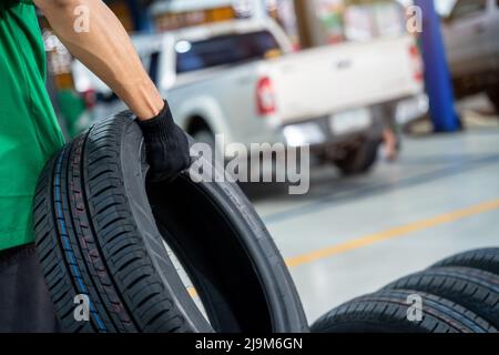 Nahaufnahme der Auto Mechanic mit neuem Reifen in der Autowerkstatt. Stockfoto
