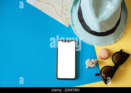 Reiseset mit Hut, Reisekarte, Smartphone und Sonnenbrille auf blauem Hintergrund Stockfoto
