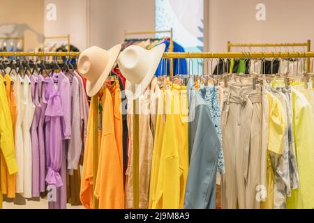 Bunte Jugendkleidung auf Kleiderbügeln im Geschäft, Sommer- und Frühlingssortiment im Bekleidungsgeschäft Stockfoto