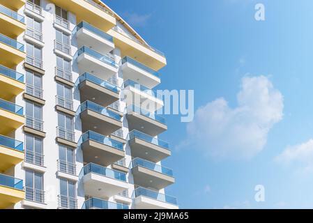 Gelbe und blaue moderne, belüftete Fassade mit Fenstern. Fragment eines neuen Wohn- oder Geschäftsgebäudes. Teil der Stadt Immobilien. Stockfoto