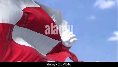 Die Flagge Grönlands winkt an einem klaren Tag im Wind. Grönland ist die größte Insel der Welt und eines der drei konstituierenden Länder, die sich bilden Stockfoto