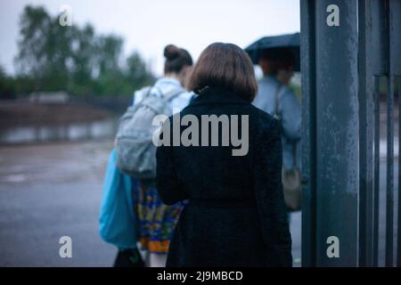 Bei bewölktem Wetter laufen die Menschen die Straße entlang. Bürger im Regen fahren zum Transport. Der Mann in der Stadt. Stockfoto