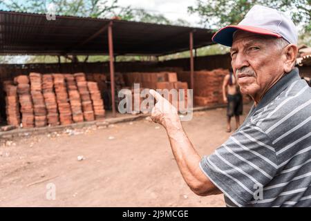 Älterer Besitzer einer Werkstatt, die einen Keller aus Ziegelsteinen zeigt, die in einem traditionellen Ofen in Nicaragua hergestellt wurden Stockfoto