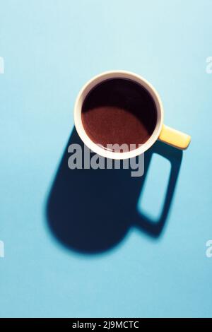 Eine Tasse heißen Kaffee in Pastellfarben. Türkischer Kaffee in einem gelben Becher auf blauem Hintergrund. Stockfoto