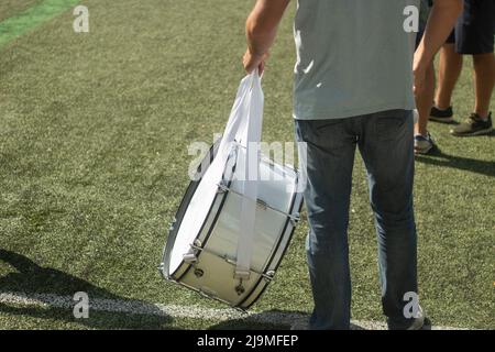 Große Trommel ist weiß. Mann beim Fußballspiel. Details des Musikinstruments. Lüfter hält Trommel. Stockfoto