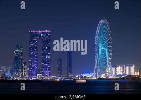 Farbenfroher Blick auf das beleuchtete Address Beach Resort und das Dubai Eye Ferris Wheel, das von der Palme Jumeirah West in Dubai, VAE, erfasst wurde. Stockfoto