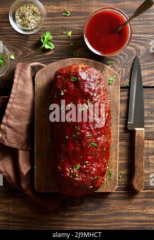 Hackbraten mit Glasur auf Schneidebrett auf Holzhintergrund. Draufsicht, flach liegend Stockfoto