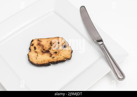 Brot, das auf einer Seite verkocht und zu einer Zünette verbrannt wurde. Bei Acrylamid und Krebs, Lebensmittel ungenügend zum Essen, schlechte Küchenkenntnisse, nicht in der Lage zu kochen. Stockfoto