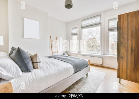 Breites, komfortables Bett mit warmen Decken und weichen Kissen im trendigen Schlafzimmer des modernen Apartments Stockfoto