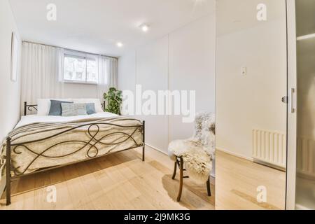 Geräumiges Schlafzimmer mit komfortablem Bett in der Nähe von großen Fenstern mit Vorhängen in einer modernen Wohnung Stockfoto