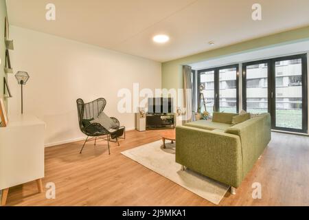 Komfortable Couch und Holzcouchtisch vor dem modernen Fernseher im gemütlichen, geräumigen Wohnzimmer im Haus an sonnigen Tagen platziert Stockfoto