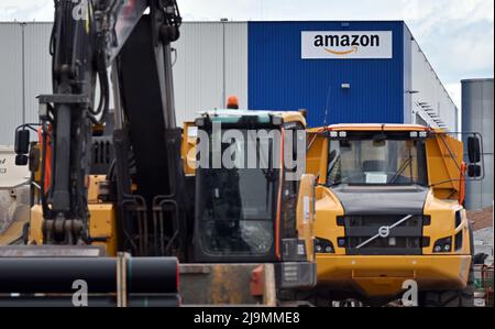 Erfurt, Deutschland. 24.. Mai 2022. Baufahrzeuge stehen auf der Baustelle neben einem Amazon-Vertriebszentrum. Hier hielten Ehrengäste und Vertreter eines Projektentwicklungsunternehmens den symbolischen Spatenstich für ein neues Logistikzentrum am Logistikstandort Erfurt-Stotternheim ab. Gewerkschafter und eine Fraktion im stadtrat kritisierten den Ausbau des Logistikstandortes. Quelle: Martin Schutt/dpa/Alamy Live News Stockfoto