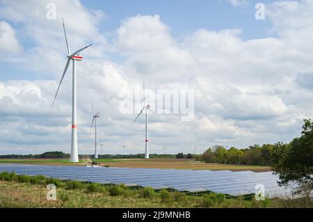 Farm mit Sonnenkollektoren und Windturbinen, vor dem Hintergrund des Himmels und der Wolken. Umweltfreundliches Energiekonzept. Stockfoto