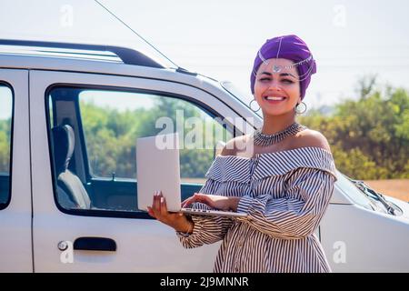 Business Afro-amerikanische Frau Unternehmerin Arbeitgeber mit Make-up in Kleid arbeiten in der Nähe von Auto mit Laptop Stockfoto