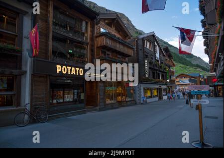 Blick auf Souvenirläden an der Haupteinkaufsstraße von Zermatt, einem autofreien Dorf mit Restaurants, lokalen Chalet-Häusern und Hotels im Sommer. Stockfoto