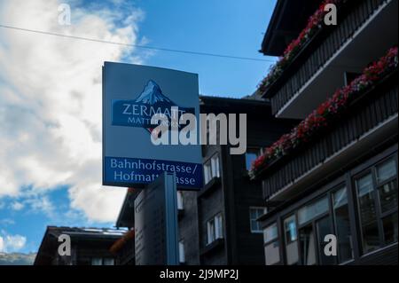 Ein Schild an der Haupteinkaufsstraße von Zermatt, das die Wegbeschreibung zu den verschiedenen Touristenzielen anzeigt. Stockfoto