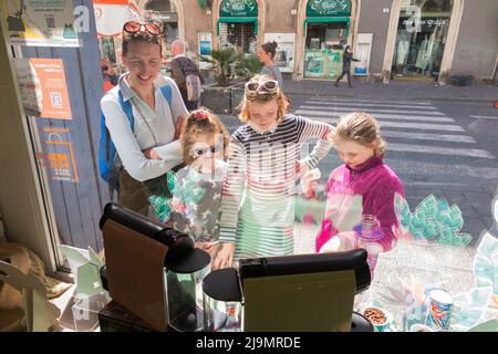 Shopping-Familie mit Mutter, Mutter und drei Töchtern, Kindern, Schaufensterbummel für Kaffeekannen und Kaffeemaschinen im Bialetti Store in Catania, Sizilien. Italien. (129) Stockfoto