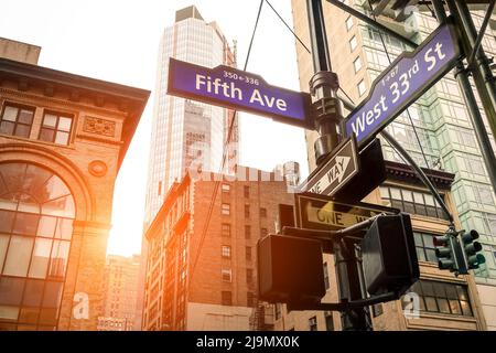 Straßenschild der Fifth Ave und West 33. St bei Sonnenuntergang in New York City - Stadtkonzept und Straßenrichtung in der Innenstadt von Manhattan Stockfoto