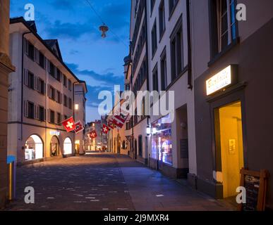 Chur, Schweiz. Malerischer Blick auf das Dorf Chur mit alten historischen Gebäuden, alpinen Bergen und dem fließenden Rhein in der Nacht Stockfoto