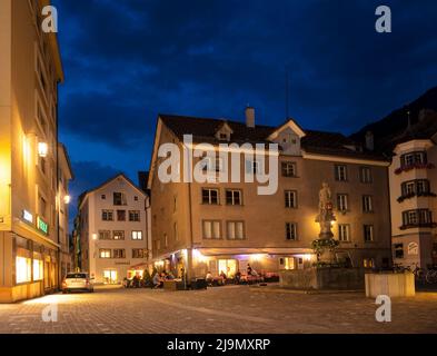 Chur, Schweiz. Malerischer Blick auf das Dorf Chur mit alten historischen Gebäuden, alpinen Bergen und dem fließenden Rhein in der Nacht Stockfoto