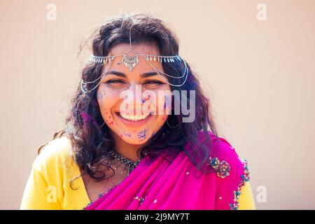 Portrait von jungen indischen Gesicht in Farbe Frau in traditionellen indischen rosa Outfit mit Juwelier feiert Holi Farbe Festival.Girl mit schwarzen Haaren mit Stockfoto