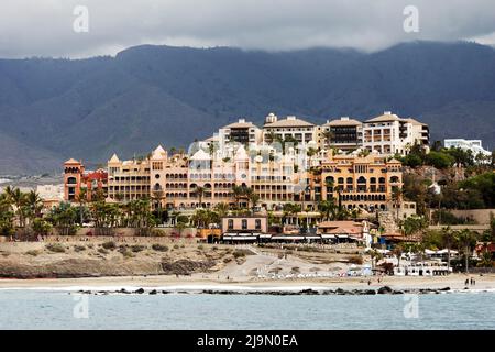 Sonnenliegen, Urlauber und Hotels an der Costa Adeje auf Teneriffa, Spanien. Die Gegend ist ein beliebtes Urlaubsziel. Stockfoto