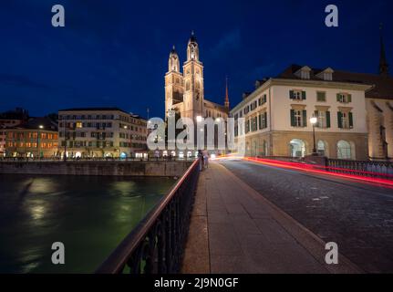 Munsterbrücke und Grossmünster Kirche über der Limmat während der Blauen Stunde in Zürich, Schweiz. Stockfoto