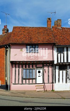 Blick auf ein rosafarbenes, mit Fachwerk gerahmtes mittelalterliches Gebäude im gut erhaltenen mittelalterlichen Dorf Lavenham, Suffolk, England, Vereinigtes Königreich. Stockfoto