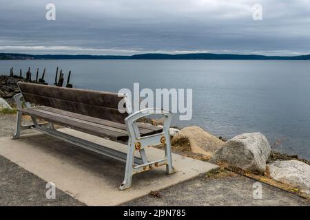 Schräg Blick hinter einer hölzernen Parkbank mit der Skyline von Tacoma am Horizont Stockfoto