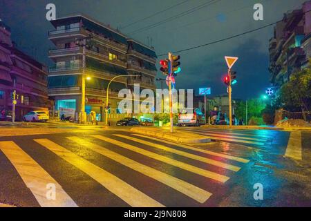 Ampel an einer regnerischen nassen Kreuzung in Athen rot. Stockfoto