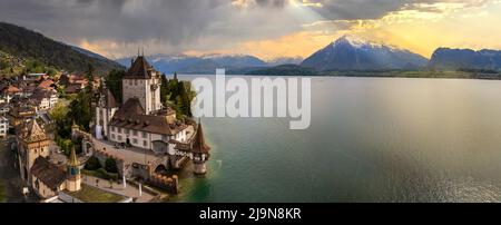 Luftaufnahme von erstaunlicher romantischer Burg Oberhofen bei Sonnenuntergang Licht. Landschaftlich schöner Thunersee, Schweiz Reisen und Wahrzeichen Stockfoto