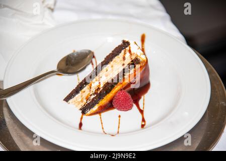 Stück Kuchen mit Schokolade in einem weißen Gericht mit einem kleinen Löffel, Nahaufnahme Stockfoto