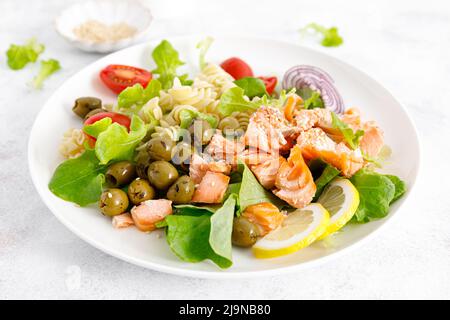 Gegrillter Lachssalat mit frischem Salat, Tomaten, grünen Oliven, roten Zwiebeln und Pasta. Gesunde Ernährung, Ernährung Stockfoto