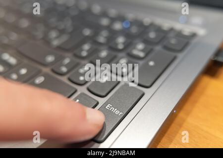 Drücken Sie mit dem Finger die ENTER-Taste auf einem Computer, einem Makrofoto. Stockfoto