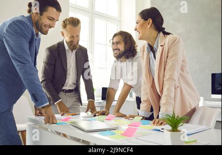 Kreative Kollegen schreiben Notizen auf bunte Aufkleber, während sie im Büro ein Geschäftsprojekt entwickeln. Stockfoto