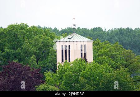 Teltow, Deutschland. 17.. Mai 2022. Der Turm der Kirche der katholischen Pfarrei Sanctissima Eucharistia ragt unter den Blättern der Bäume hervor. Quelle: Soeren Stache/dpa/Alamy Live News Stockfoto