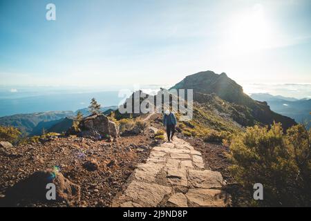 Wanderweg unter dem Berg Encumeada Baixa mit Ziel auf dem höchsten Berg Madeiras, dem Pico Ruivo. Die Sonne scheint auf der Seite des Madeira Stockfoto