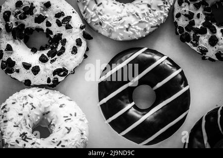 Flach Lay Bild von Donut mit Schokolade Glasur mit Streifen Amids andere verschiedene Donuts - schwarz-weiß-Bild Stockfoto