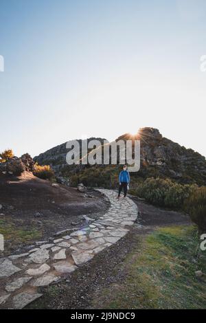 Wanderweg unter dem Berg Encumeada Baixa mit Ziel auf dem höchsten Berg Madeiras, dem Pico Ruivo. Die Sonne scheint auf der Seite des Madeira Stockfoto