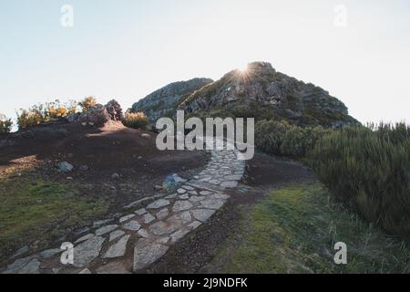 Wanderweg unter dem Berg Encumeada Baixa mit einem Ziel auf Madeiras höchstem Berg, dem Pico Ruivo. Die Sonne scheint auf der Seite des Madeir Stockfoto