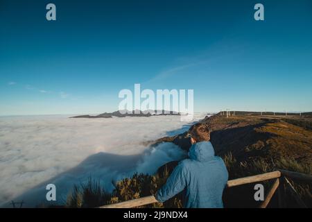 Touristen beobachten, wie die höchsten felsigen Berge der Insel Madeira aus den Wolken in den Sonnenuntergang vom Aussichtspunkt des Pico Ruivo do Paul aufsteigen. Stockfoto