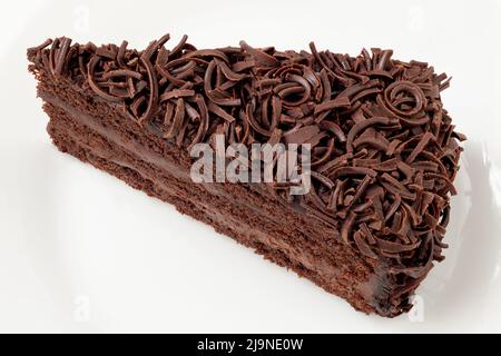 Scheibe Schokoladenkuchen mit Sahnefüllung und auf weißem Teller isoliertem Schokoladenspan. Draufsicht. Stockfoto