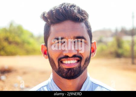 Porträt von schönen beiläufigen indischen männlichen schneeweißen lächelnden Diamant-Ohrring im Piercing-Ohr, Gesichtskosmetologie Barbershop Bart Stockfoto