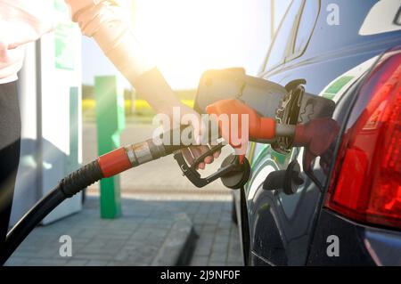 Tanken Sie das Auto auf. Eine Frau an einer Tankstelle betankt das Auto an einem sonnigen Sommertag mit Kraftstoff. Stockfoto