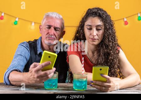 Schöne Frau mit lockigen Haaren und sein Vater im Chat mit dem Smartphone - Studioaufnahme Stockfoto
