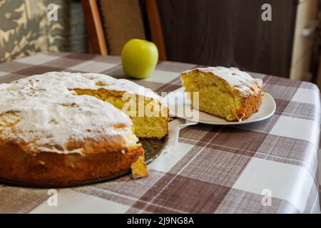 Heißer klassischer Apfelkuchen und sein Stück auf weißem Teller mit Dampf Stockfoto