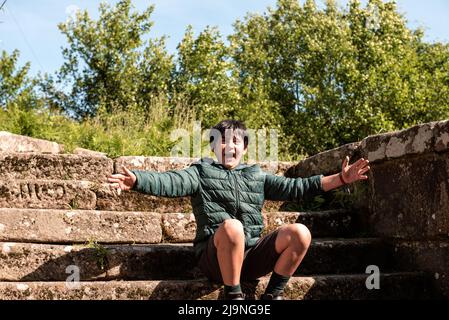 Kleiner Junge, der auf einer Steintreppe in spanien sitzt Stockfoto