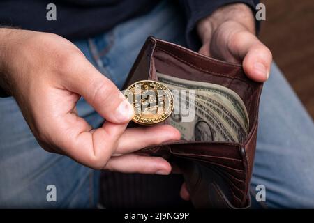 Bitcoin in der Hand und offene Brieftasche mit Dollar Stockfoto