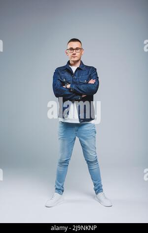 Leben Sie ein reiches Leben. Positive Emotionen. Porträt eines jungen attraktiven Mannes in einem weißen T-Shirt und einer Jeansjacke. Herrenbekleidung aus der Denim-Kollektion Stockfoto